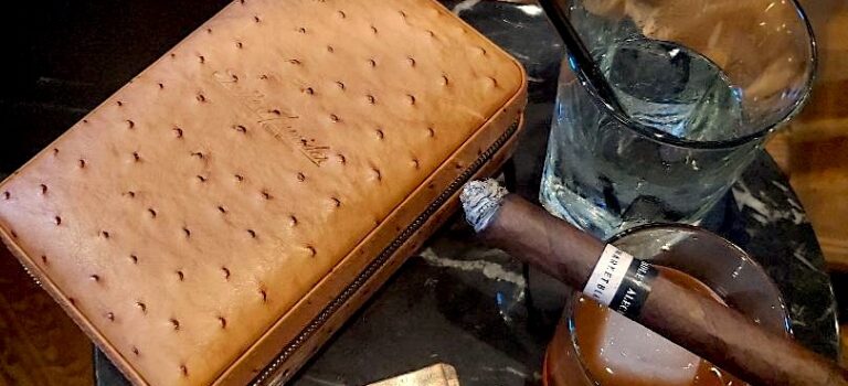 10 Weekend Rituals Every Cigar Enthusiast Should Experience Premium cigar, cocktail, cutter, and travel humidor arranged on a lounge table, representing weekend rituals and the cigar lifestyle.